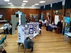 Image of people standing next to tables and stalls in hall